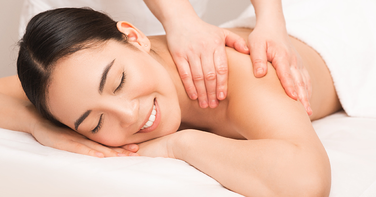 A relaxed woman smiling with eyes closed while receiving Massage Therapy in Springfield, MO